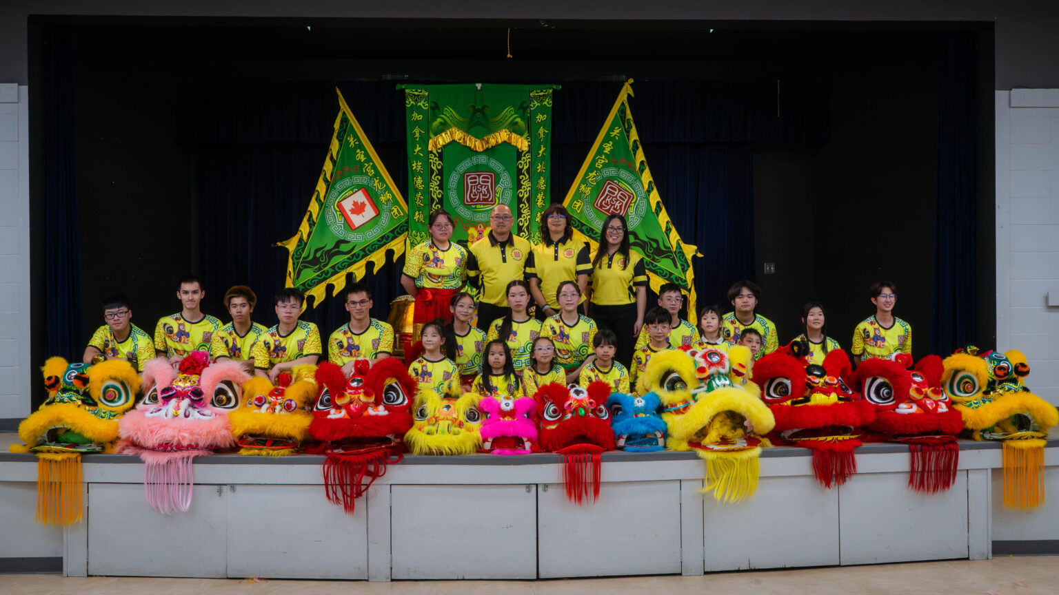 Photo of Edmonton KSK team members and board members standing on stage posing with Chinese lion dance lions in the foreground.